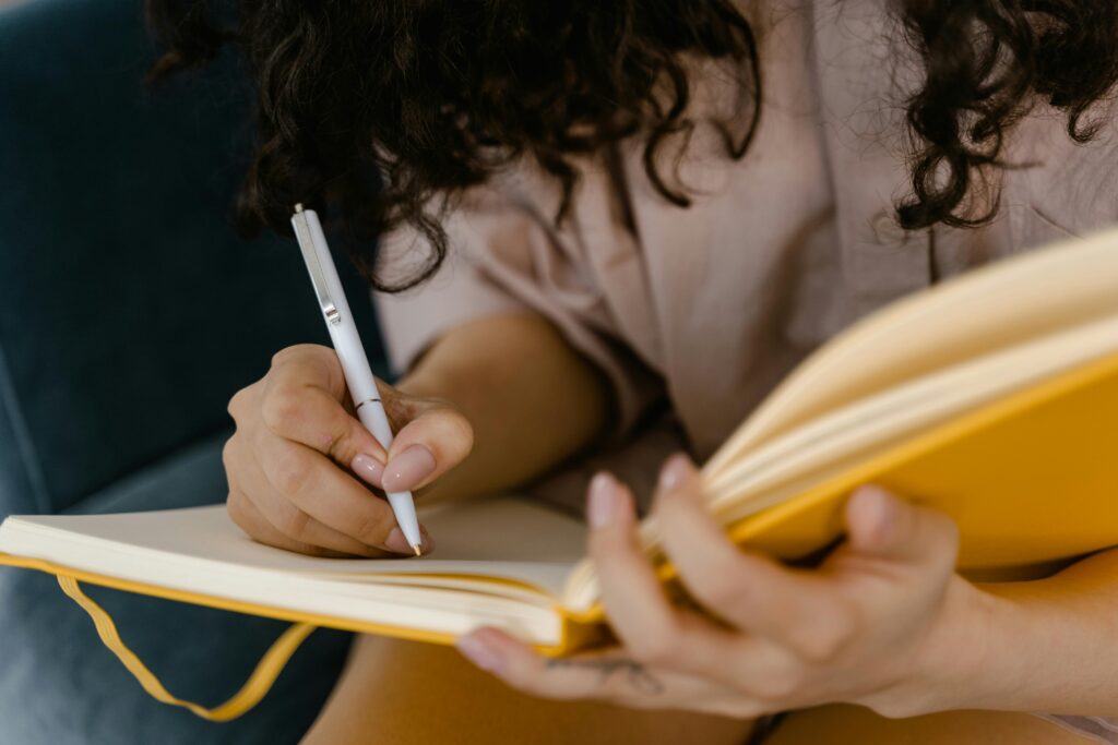 Person writing in journal to process emotions for motivation.