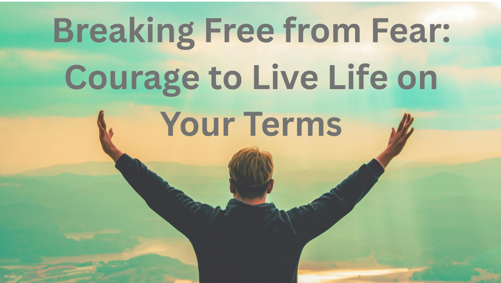 Person on mountain peak with arms raised, symbolizing overcoming fear and freedom.